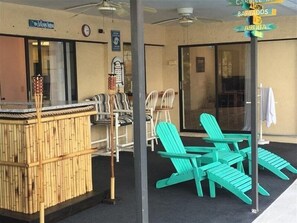Ein Außenbereich mit Sitzgelegenheiten, einer Bambar, Stühlen und einem Schild mit Wegweisern nach Barbados und Aruba.