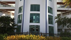 A multi-story building with large windows and a central entrance. - Beautiful luxury apartment, 3 suites, 55" TV, swimming pools, air conditioning, complete, 400m from the beach, cond. (Aquiraz)