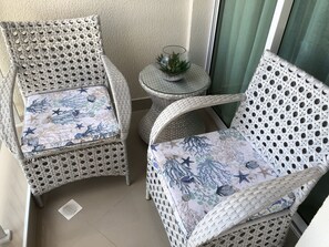 Um espaço de canto com cadeiras de vime e uma mesa pequena, com uma tigela de vidro e uma planta.