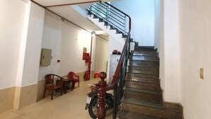 A staircase with a wooden handrail and a metal railing, leading to an upper floor.