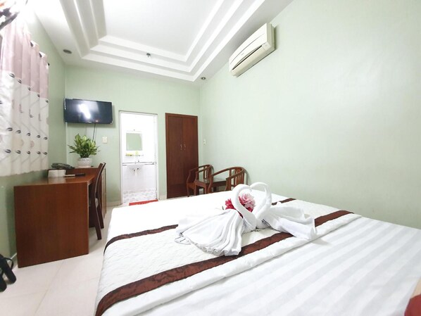 Una habitación de hotel con cama, escritorio, silla, televisor y armario.