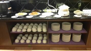 A buffet counter with various dishes and bowls of food.