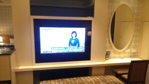 A television mounted on a wall with a news broadcast, a mirror above it, and a patterned bench below. - Chateau Motel & Spa - Daliao (Kaohsiung)
