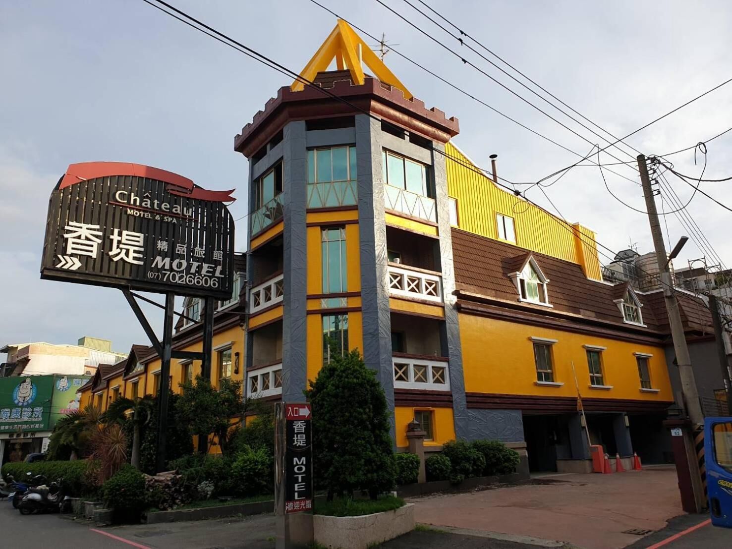 Un hotel con un letrero destacado en inglés y chino, que presenta un diseño moderno con colores amarillo y marrón.