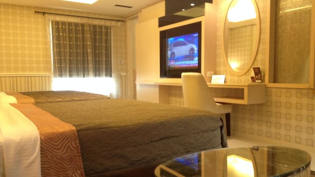 A hotel room with a bed, a TV, a desk, and a glass table. - Chateau Motel & Spa - Daliao (Kaohsiung)