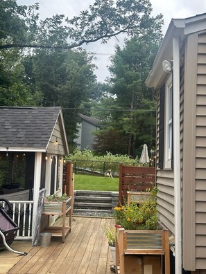 A wooden deck with outdoor seating, a small porch, and a garden area with a wooden fence and potted plants.