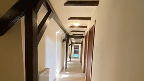 A long, narrow hallway with wooden beams on the ceiling and a radiator on the left wall.