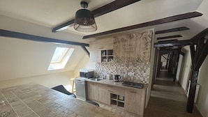 A modern kitchen with a built-in oven, microwave, and coffee maker. There is a small window above the sink and a wooden backsplash with a nature-themed design.