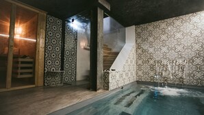 Un espace bien-être comprenant un jacuzzi, un revêtement de sol en bois et des murs décorés de motifs.