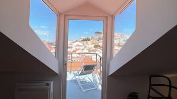 A room with a sloped ceiling, a skylight, a radiator, and a view of buildings through the skylight.