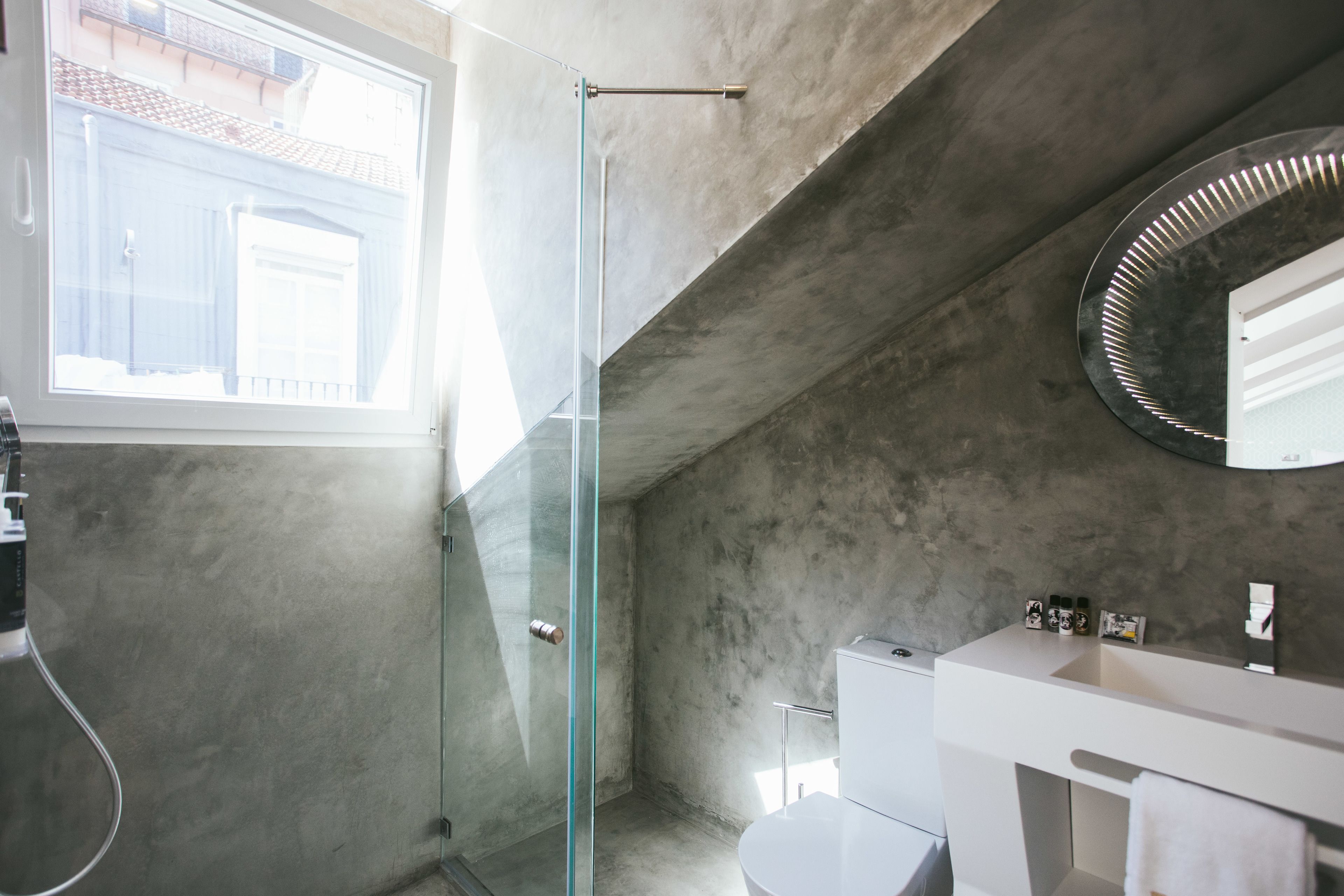 Une salle de bain moderne avec une douche à l’italienne en verre, un lavabo blanc et un grand miroir.