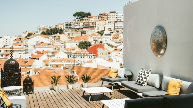 Une terrasse sur le toit offrant une vue sur le paysage urbain, aménagée avec un canapé, des coussins et un petit foyer.