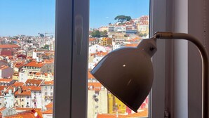 Une fenêtre donnant sur un paysage urbain, une lampe et un chambranle de porte blanche.