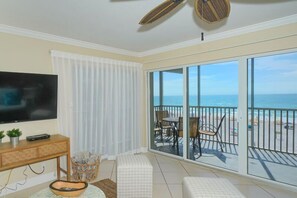 Relax on the balcony with a view of the ocean, enjoying the spacious living area and flat-screen TV.
