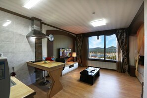 A modern kitchen with a dining area, a large window with a view, and a cozy seating area. - Illua Pension (Tongyeong)