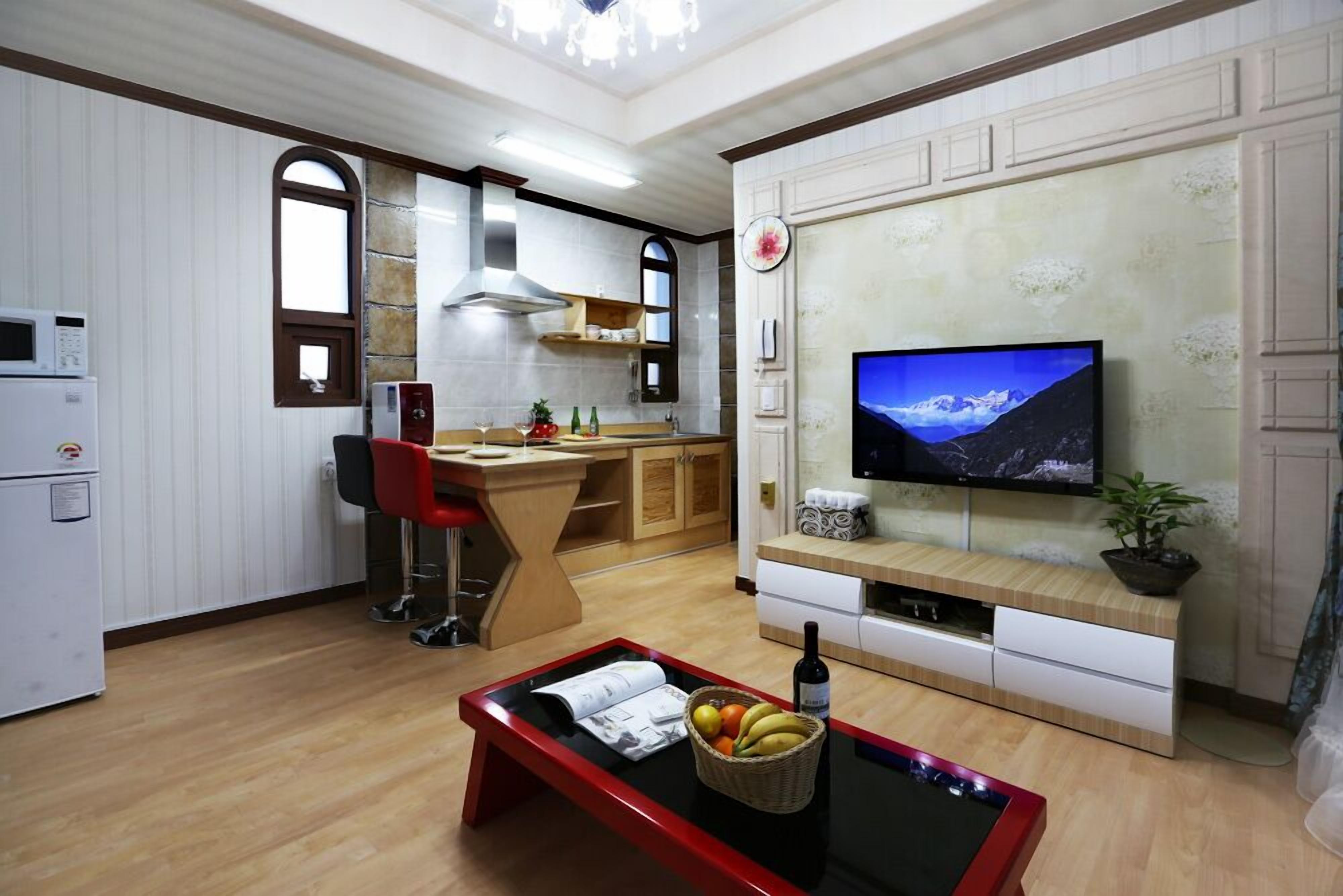 Um espaço de estar compacto com cozinha, área de jantar e uma TV fixada na parede.