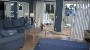 Ein Wohnzimmer mit einer Couch, einem Couchtisch und einer Glasschiebetür, die auf eine Terrasse führt.
