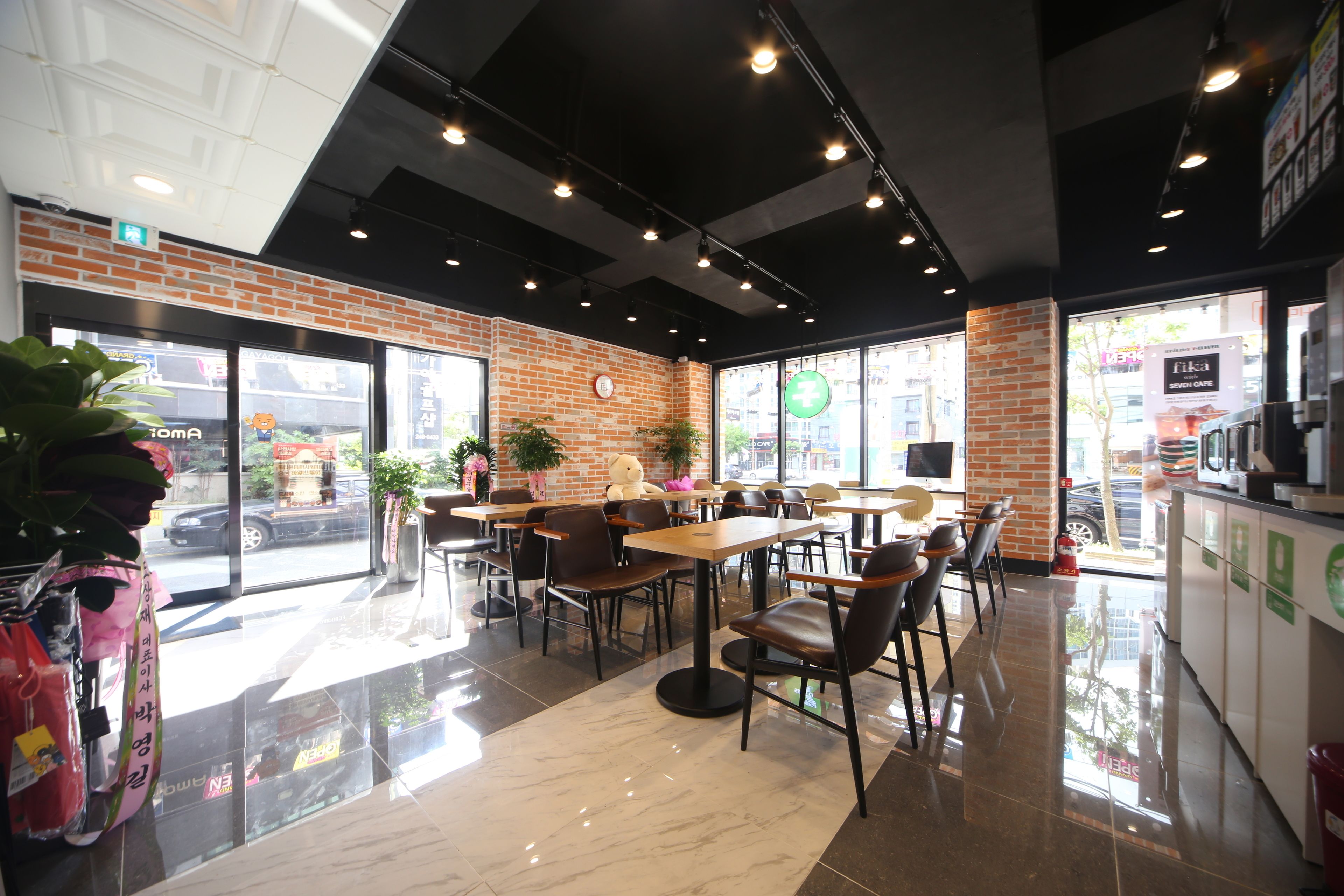 A modern cafe with brick walls, large windows, and a clean, polished floor.