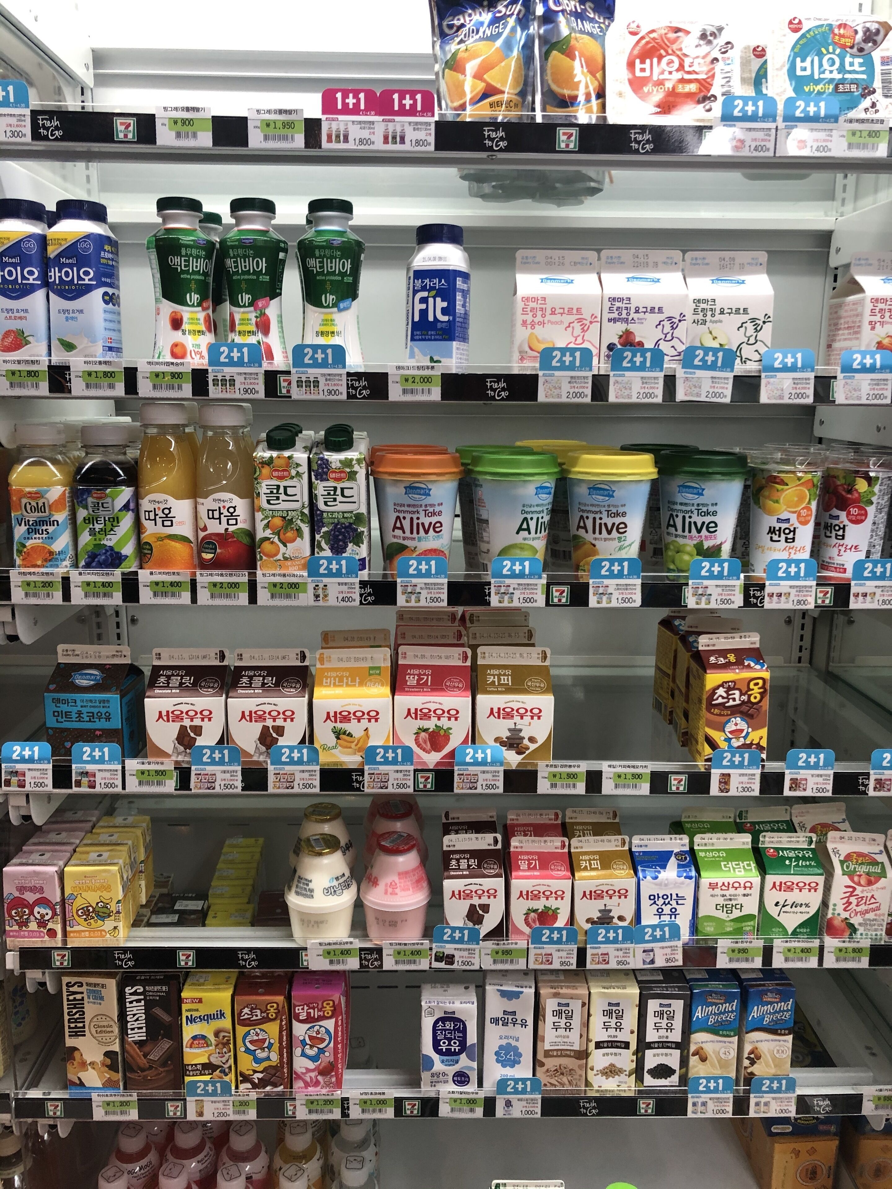 A grocery store shelf stocked with various dairy products, including milk, yogurt, and juice.