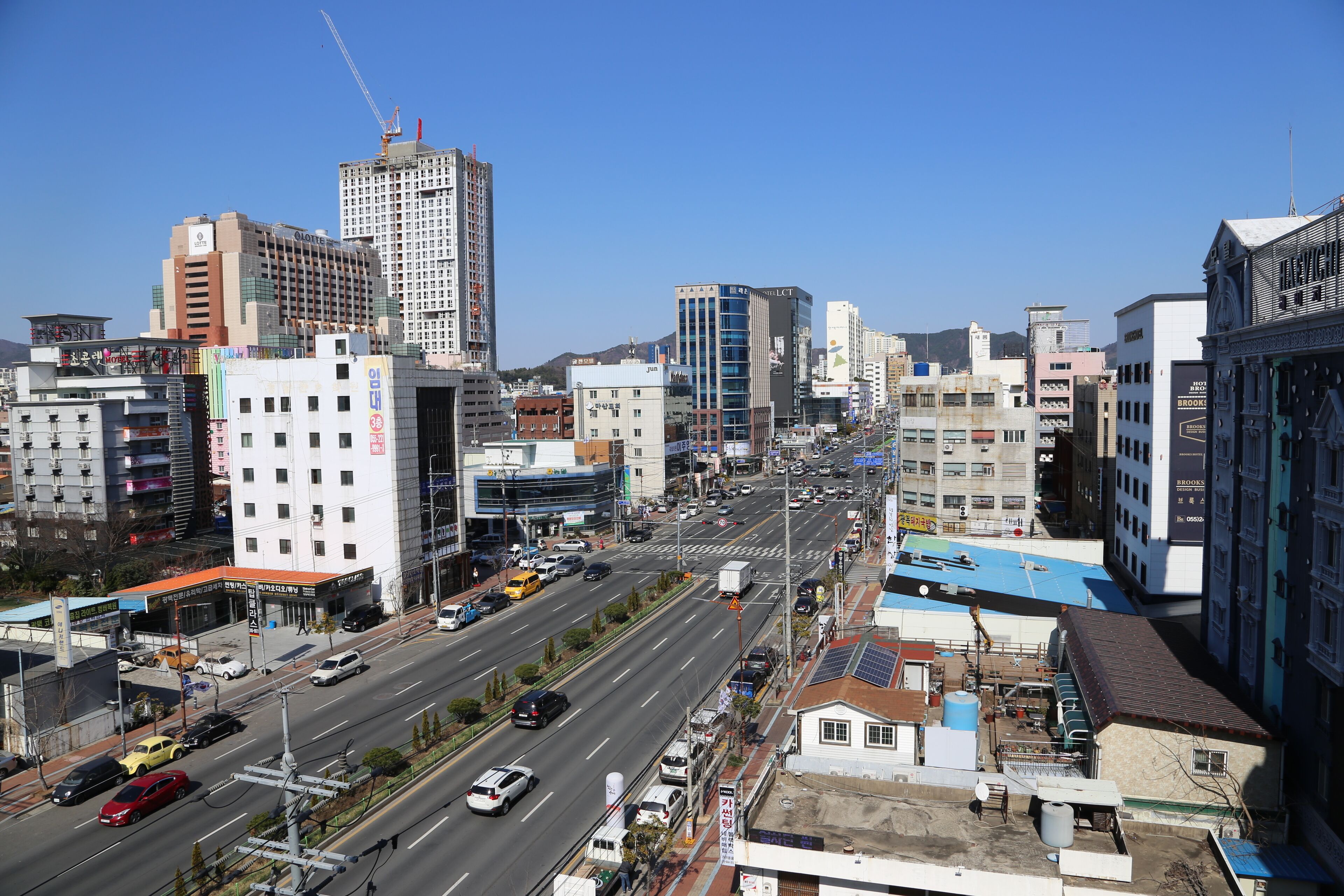 Un paisaje urbano con una avenida ancha, varios edificios y una grúa de construcción.