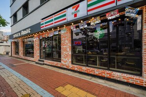 A 7-Eleven convenience store with a brick facade and large windows. - Masan Amor Hotel (Changwon)
