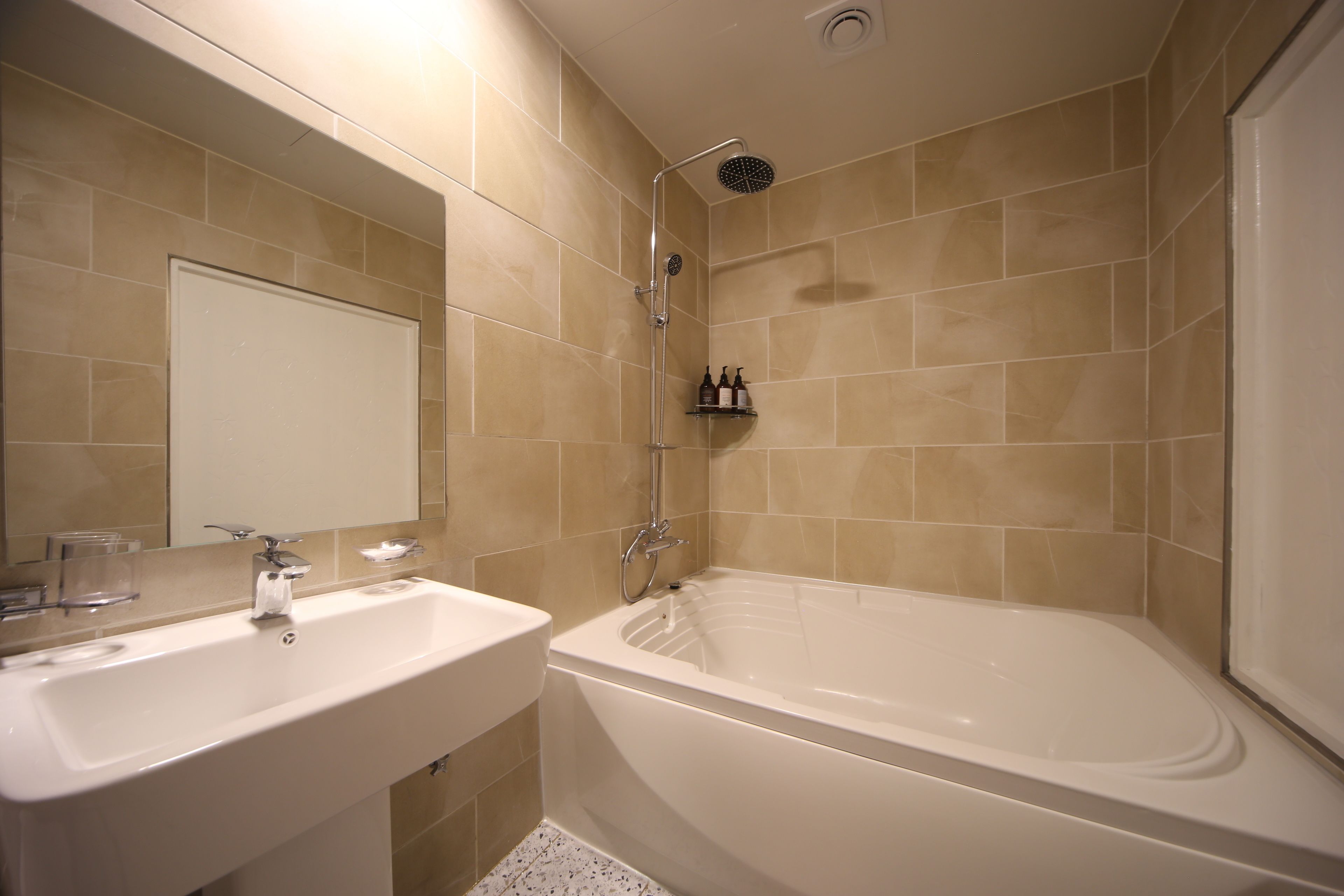 Un baño con lavamanos, espejo y bañera.