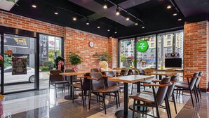 A modern cafe with brick walls, large windows, and a variety of seating arrangements. - Masan Amor Hotel (Changwon)