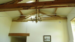 A room with exposed wooden beams, a chandelier, and a framed picture on the wall.
