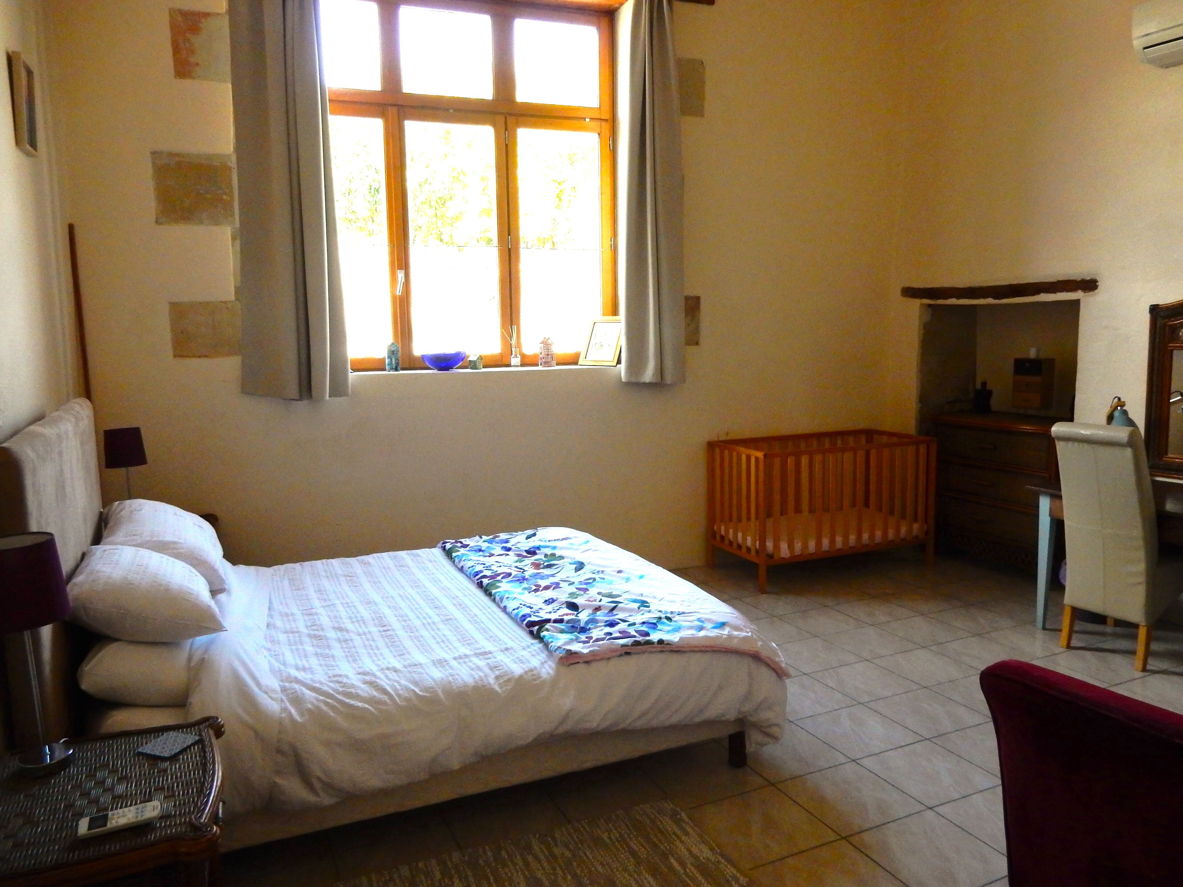 Ein Schlafzimmer mit einem Bett, einem Babybett, einem Schreibtisch und einem Stuhl.