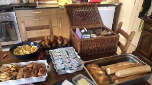 A table with various food items including bread, pastries, cheese, and cured meats.