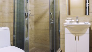 Un baño moderno con ducha de vidrio, inodoro y lavabo con espejo.