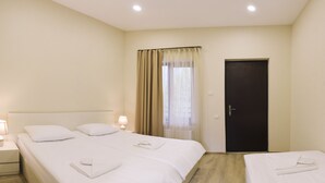 Una habitación de hotel con dos camas, una puerta oscura y una ventana con cortinas.