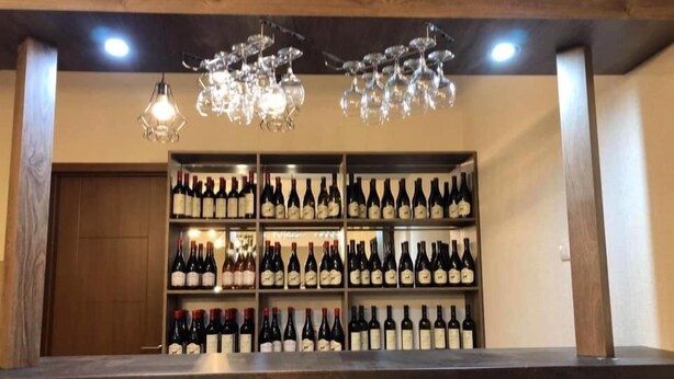 Zona de bar con estanterías llenas de botellas de vino y una lámpara colgante.