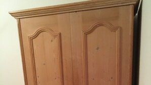 Ein hölzerner Kleiderschrank mit zwei Türen, einem Griff und einem Schloss.