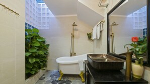 Ein Badezimmer mit einer freistehenden Badewanne, einem großen Spiegel und einem Waschbecken mit einer Haube.
