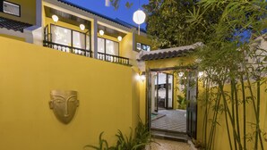 Ein gelbes Gebäude mit Balkon, ornamentalem Wandverkleidung und gefliestem Eingang.