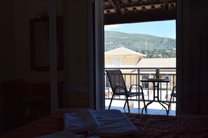 Un dormitorio con cama, ventana y vista a un balcón con sillas y una mesa.