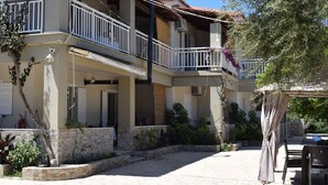 A multi-story building with balconies, outdoor seating, and a stone pathway. - Villa Miranda (Zakynthos)