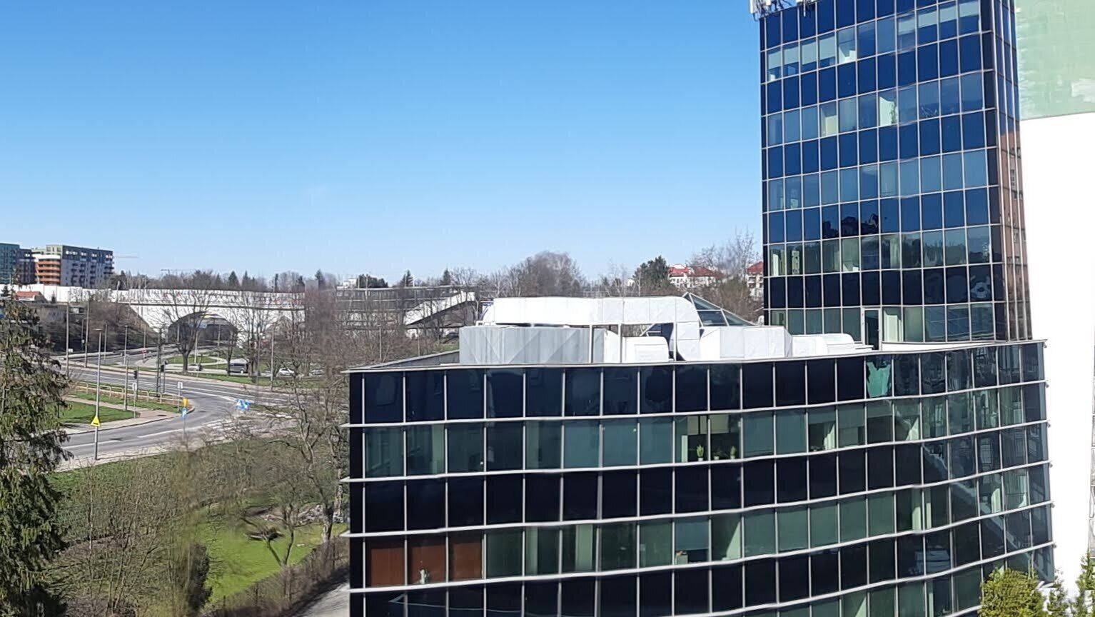 Un edificio moderno de cristal con vistas despejadas del paisaje urbano circundante, que incluye una calle y edificios a la distancia.