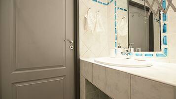 A bathroom with a white door, a sink with a mirror, and blue-tiled walls.