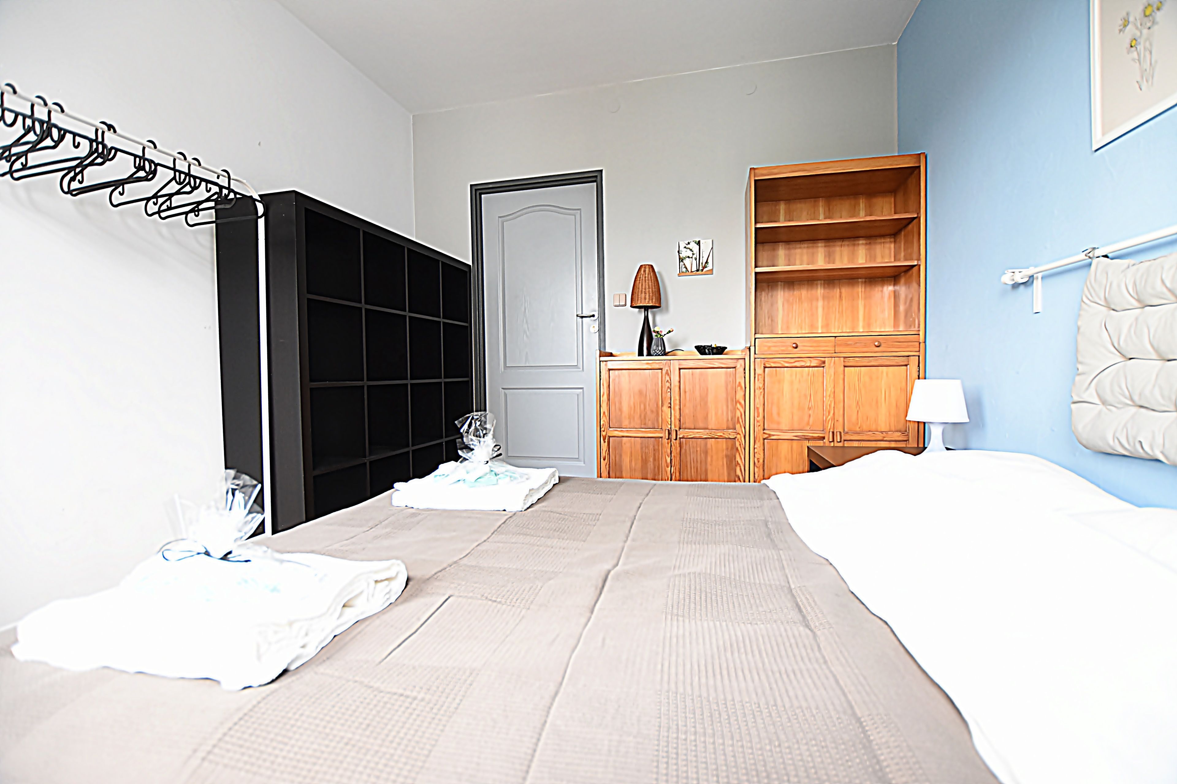 A bedroom with a bed, a wardrobe, a bedside table, and a lamp.