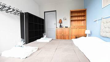 A bedroom with a bed, a wardrobe, a bedside table, and a lamp.