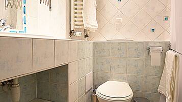 Un baño con inodoro, lavabo, espejo, toallero y cubo de basura.
