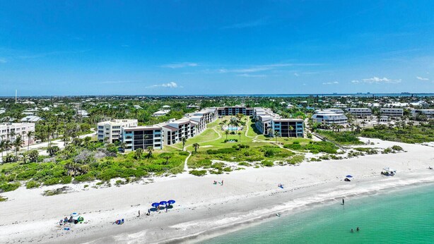 A resort with multiple buildings, a beach, and a clear blue sky. - Loggerhead Cay 562 - Partial gulf view, beach side vacation rental condo (Sanibel)