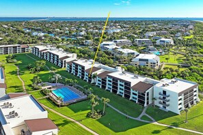 A residential area with a row of modern houses, a swimming pool, and a view of the ocean. - Loggerhead Cay 562 - Partial gulf view, beach side vacation rental condo (Sanibel)