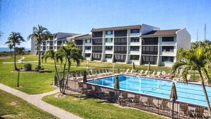 Ein Hotel mit Swimmingpool, Palmen und blauem Himmel.