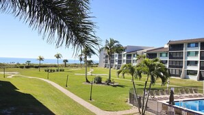 A resort with a swimming pool, palm trees, and a view of the ocean. - Loggerhead Cay 562 - Partial gulf view, beach side vacation rental condo (Sanibel)