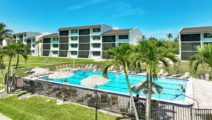 Ein Hotel mit Swimmingpool, umgeben von Palmen und Liegestühlen.