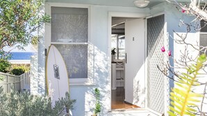 Ein Küsteneigentum mit einem Surfbrett, das an der Wand lehnt, einem Fenster und einer Tür zu einem Innenraum.