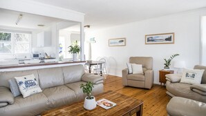 Ein modernes Wohnzimmer mit einer Couch, Sesseln, einem Couchtisch und einem Essbereich mit Tisch und Stühlen.